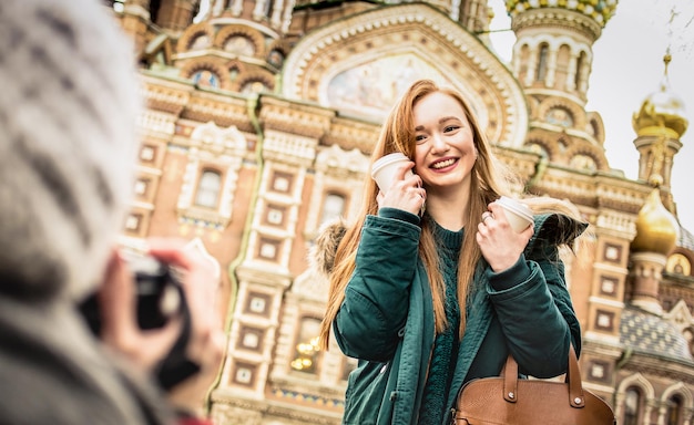 Novias felices tomando fotos de viajes de invierno en la iglesia Salvador sobre la Sangre Derramada en San Petersburgo