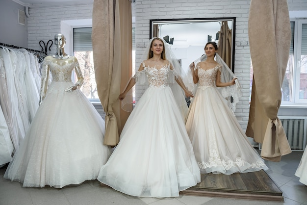 Novias felices en vestidos de novia posando en el salón