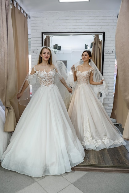 Novias felices en vestidos de novia posando en el salón