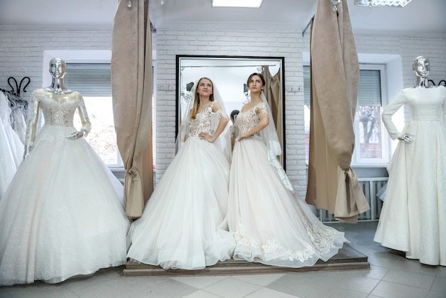 Novias felices en vestidos de novia posando en el salón