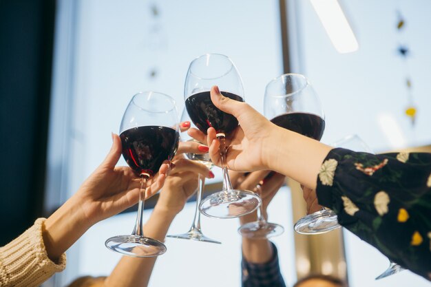 Novias de fiesta y con copas de vino tinto.