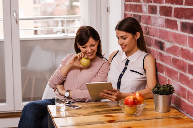 Novias sentadas juntas y sosteniendo la tableta