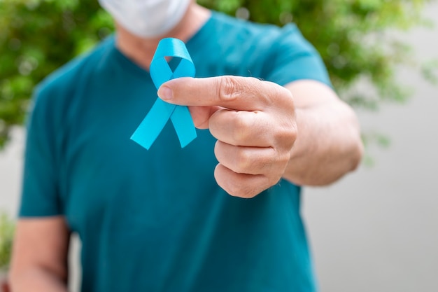 Noviembre azul Salud de los hombres Mes de la prevención del cáncer de próstata hombre que sostiene la cinta azul