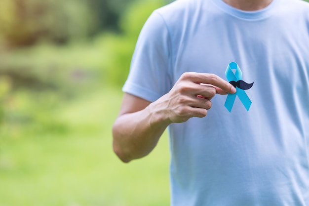 Foto noviembre mes de concientización sobre el cáncer de próstata, hombre adulto que sostiene la cinta azul con bigote para apoyar a las personas que viven y están enfermas. concepto de salud, hombres internacionales, padre y día mundial del cáncer