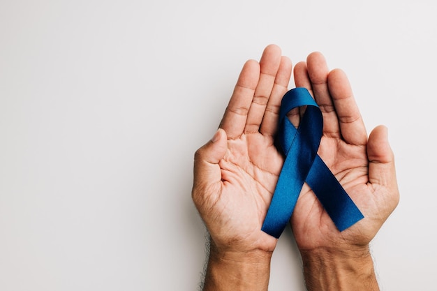 En noviembre, se sostiene en las manos una cinta azul que simboliza la salud de los hombres y la concienciación sobre el cáncer de próstata sobre un fondo blanco. Un recordatorio conmovedor para todos, especialmente para los padres.