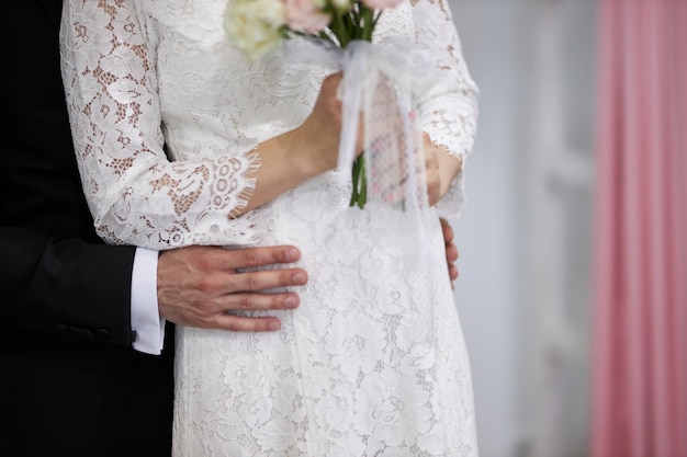 el novio abraza a la novia por la cintura de cerca