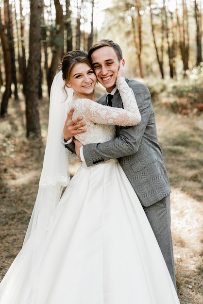 El novio abraza a la novia con una sonrisa en su rostro. precioso día de la boda de una linda pareja. boda rústica. novia rubia. boda internacional. Pareja europea.