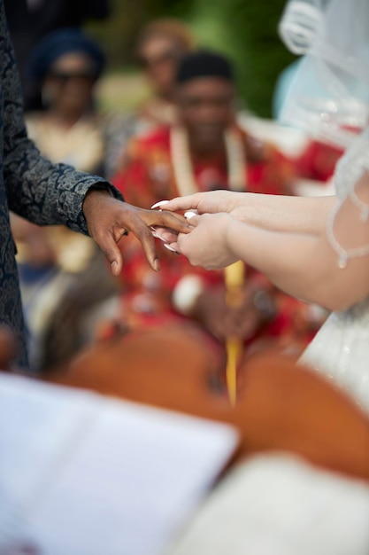 Novio afroamericano y novia caucásica La novia pone un anillo en el dedo del novio Diversidad