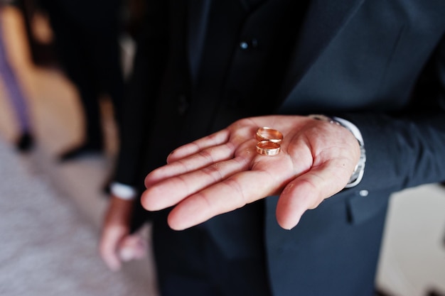 Novio con anillos de boda en la mano