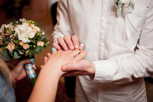 El novio de los anillos de intercambio de recién casados pone el anillo en la mano de la novia en la oficina de registro de matrimonio