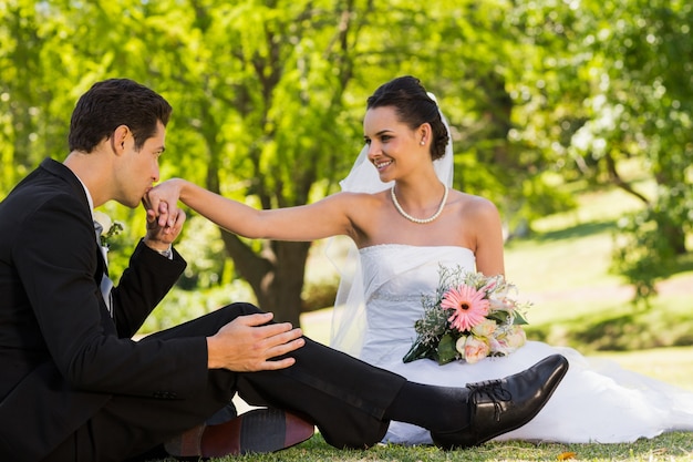 Novio besando la mano de su novia en el parque