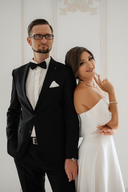 El novio con corbata de traje negro y la novia en un estudio luminoso