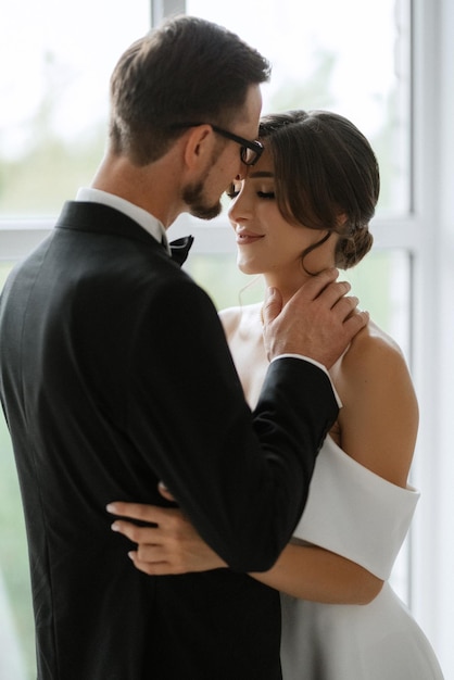 El novio con corbata de traje negro y la novia en un estudio luminoso