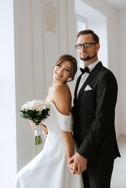 El novio con corbata de traje negro y la novia en un estudio luminoso