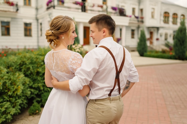 El novio elegante y la novia feliz se abrazan y se miran. Día de la boda.