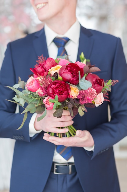 Novio elegante sosteniendo un ramo de novia