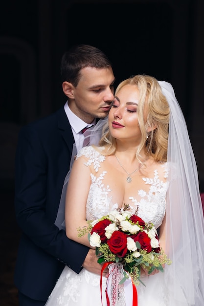 el novio con un elegante traje abraza a la novia desde atrás