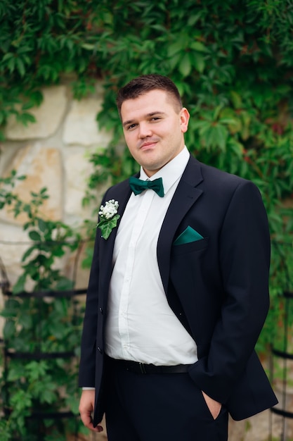 El novio con un elegante traje tiene la mano en el bolsillo y mirando a la cámara