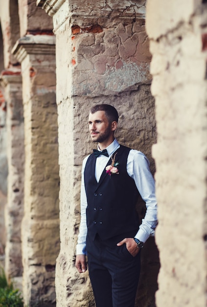 Novio en esmoquin de boda sonriendo y esperando novia