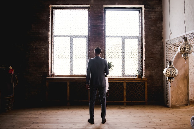 El novio está esperando a la novia con un traje gris.