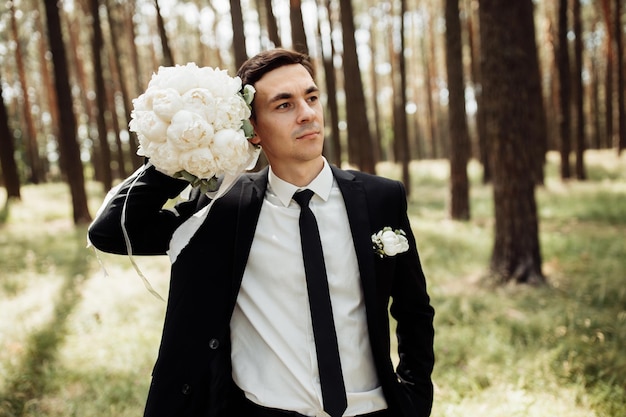 Novio guapo y divertido posando en la naturaleza novios retrato concepto de día de boda