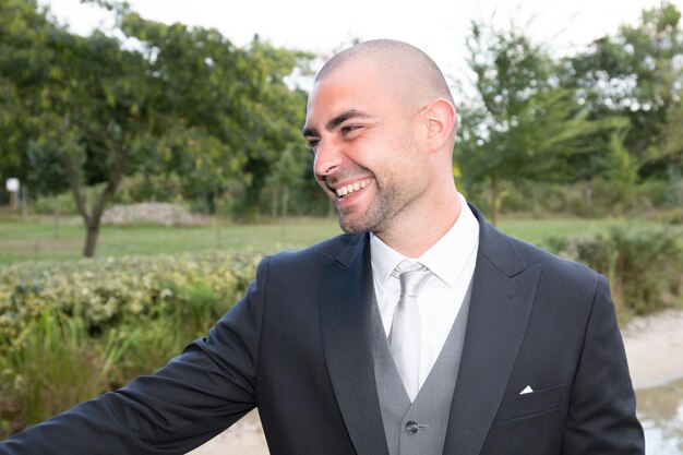 Foto novio guapo en esmoquin de boda sonriendo y esperando a la novia.