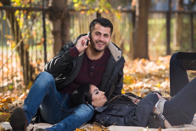 Novio hablando por teléfono mientras disfruta de Autumn Park