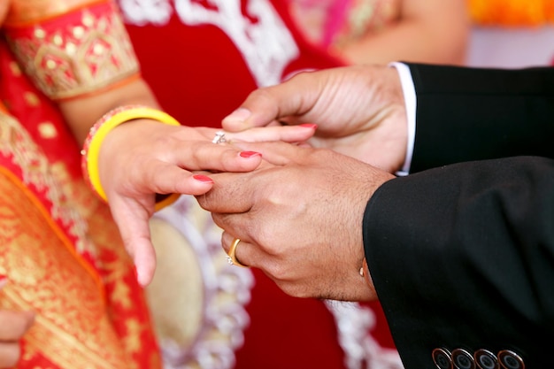 Novio indio poniendo el anillo en la novia india