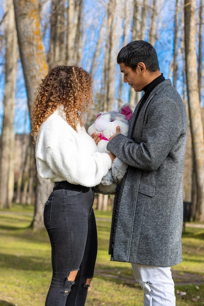 Novio latino dando un peluche a su novia el día de San Valentín