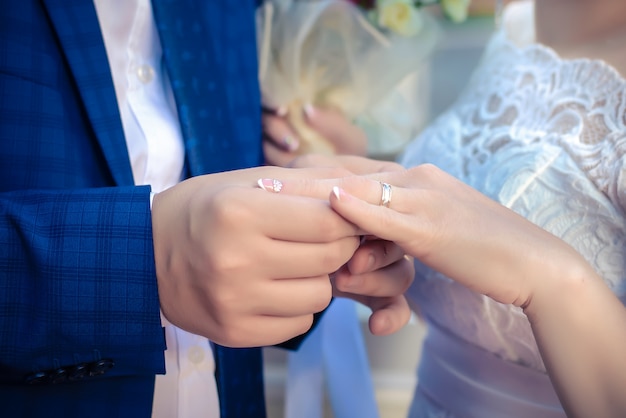 El novio lleva anillo de bodas para la novia.