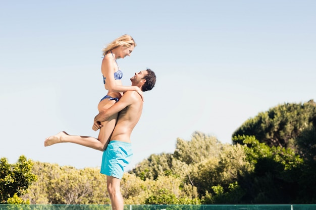 Novio llevando a su novia junto a la piscina