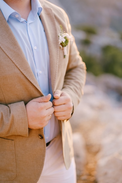 El novio mantiene sus manos en las solapas de su chaqueta closeup