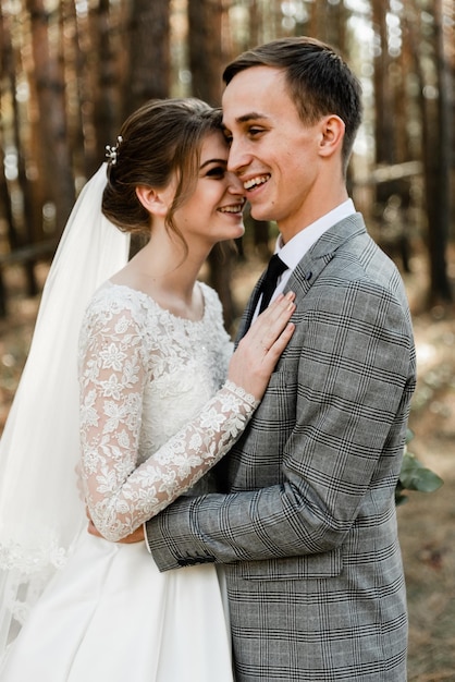 El novio y la novia se abrazan con fuerza por un fuerte amor. los recién casados están caminando por el bosque. caminar en el parque de una pareja de novios. feliz matrimonio.