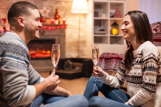 Novio y novia alegres con una gran sonrisa tintineo de una copa de champán el día de Navidad. .