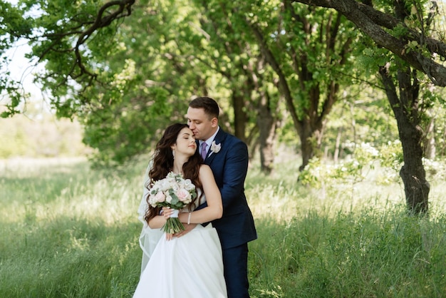 El novio y la novia caminan por el bosque.