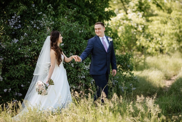 El novio y la novia caminan por el bosque.