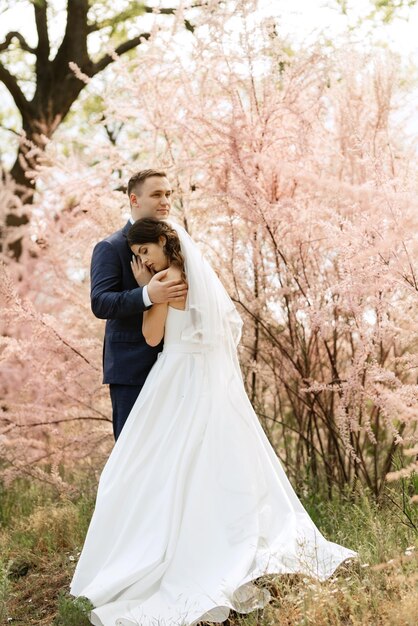 El novio y la novia caminan por el bosque.