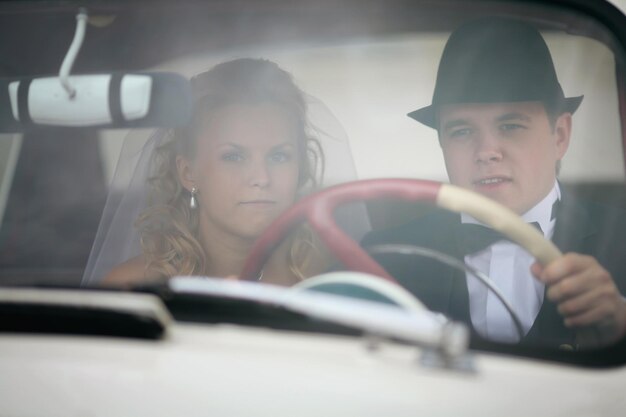 Foto el novio y la novia en un coche vintage blanco