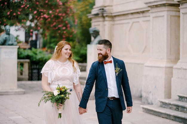 El novio y la novia están caminando en el jardín cerca de la antigua villa