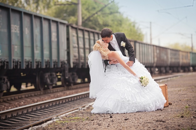 El novio y la novia con una maleta en la estación de tren