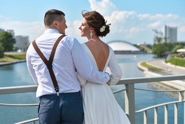 Novio con la novia en el puente de la ciudad.