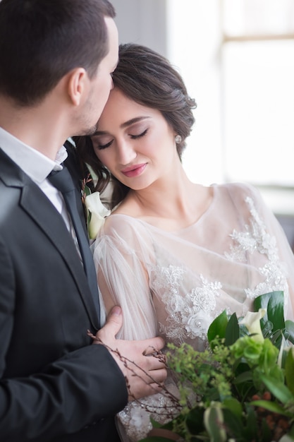 Novio y novia con ramo de novia se abrazan por las manos