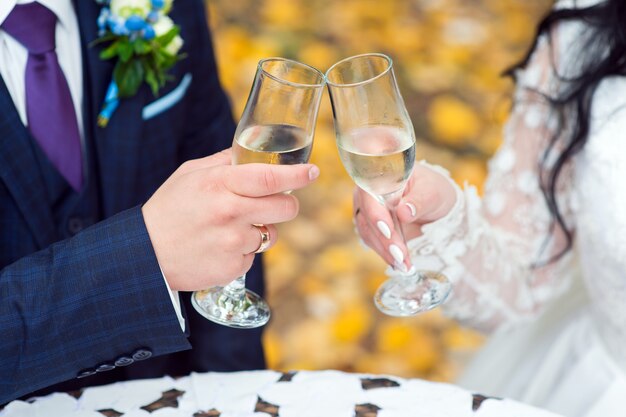 El novio y la novia sostienen vasos en primer plano de sus manos