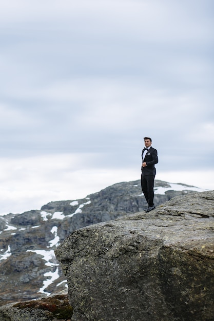 Novio de pie en la cima de una montaña en Noruega