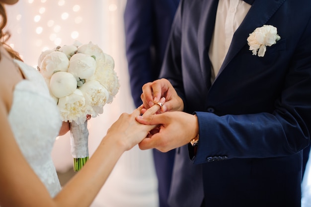 El novio se pone un anillo de bodas en el dedo de una bella novia