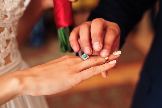 El novio y pone un anillo de bodas en el dedo de la novia.