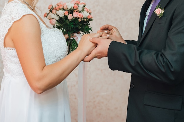 Novio pone un anillo de bodas de oro en el dedo de la novia