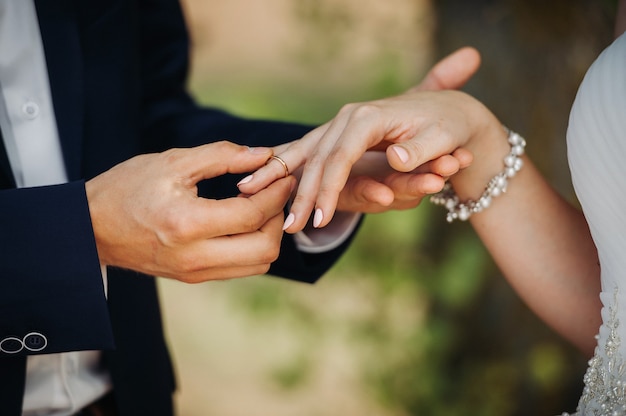 El novio pone un anillo de compromiso en el dedo de la novia el día de su boda.