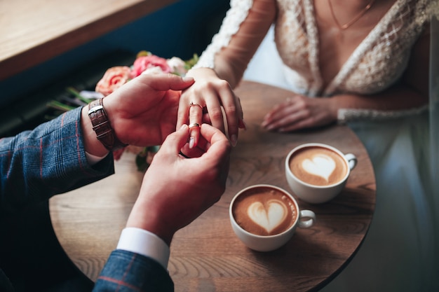 El novio pone un anillo en la mano de su esposa.