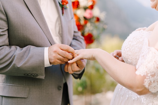 El novio pone el anillo en el primer plano de la mano de la novia